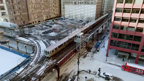 Static-aerial-view-of-a-train-on-snowy-rails-in-downtown-Chicago,-winter-in-USA