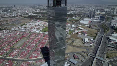 Moving-backward-of-the-view-of-the-drone-to-appreciate-the-tower-JV-and-the-main-avenue-in-Puebla,-Mexico