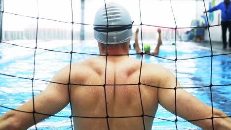 Männlicher-Wasserballsportler-Mit-Starkem-Rücken,-Der-Im-Tor-Auf-Den-Angriff-Der-Gegnerischen-Mannschaft-Wartet