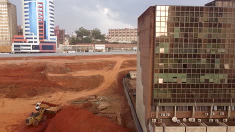 Baustelle-An-Einem-Glänzenden-Gebäude-Mit-Glasfassade,-Yaoundé,-Kamerun,-Pan-Luftaufnahme