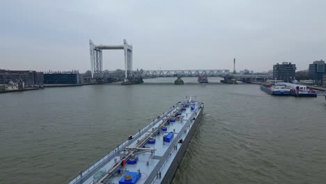 Antena-Sobre-Colorado-Tierra-Adentro-Buque-De-Carga-Líquida-Navegando-Hacia-El-Puente-Ferroviario-Spoorbrug-En-Segundo-Plano.