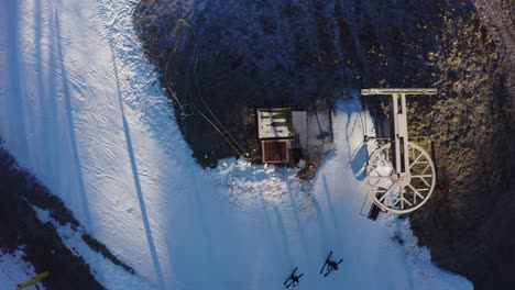 4K-Drohne-Aus-Der-Luft,-Grasbewachsene-Filmaufnahme-Von-Oben-Nach-Unten,-Von-Skifahrern,-Die-Aus-Einem-Sessellift-Steigen