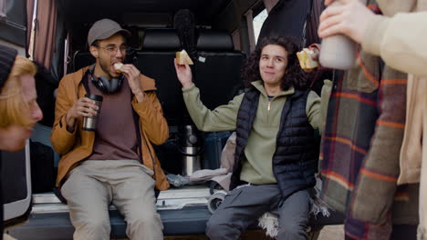A-movie-production-team-taking-a-break-while-eating-a-sandwich-and-talking-behind-a-van-in-the-street