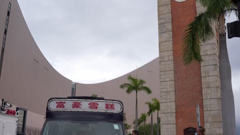 Camión-De-Helados-Icónico-En-Tsim-Sha-Tsui-Debajo-De-Un-Edificio-Y-Gente-En-Línea