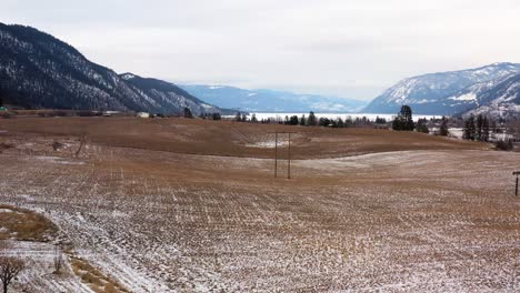 Aerial-Shot-of-Power-lines-running-over-Fields-close-to-Chase,-British-Columbia-in-the-winter