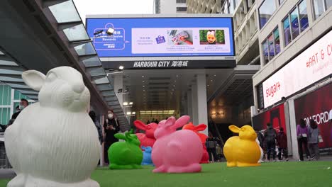Harbor-City-in-Hong-Kong-on-the-year-of-the-rabbit,-colors-sculptures-of-rabbits,-people-with-face-masks-walking-around