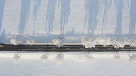 Still-aerial-shot-of-a-road-cutting-through-a-snowy-field