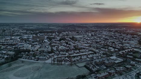 Filmische-Luftaufnahme-Im-Morgengrauen-Des-Winters-In-Yorkshire,-Die-Ländliche-Wohnhäuser-Und-Frostbedeckte-Dächer-Zeigt,-Während-Die-Morgensonne-Durch-Die-Wolken-Bricht