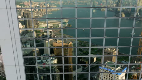 Aufschlussreiche-Seitliche-Aufnahme-Entlang-Der-Spiegelnden-Fenster-Der-Bank-Of-China-–-Victoria-Harbour-Und-Die-Skyline-Von-Hongkong-Im-Hintergrund