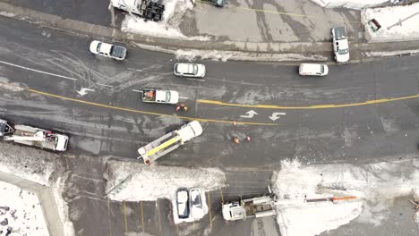 Aerial-view-of-workers-repairing-the-power-line-beside-the-road-during-the-snow-season