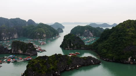 Halong-Bay-Vietnam-fishing-boats-and-fisher-viallage-drone-video-over-sea-and-green-limestone-pillars-mountain