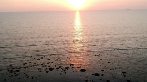 Goldene-Stunde-Des-Sonnenuntergangs-Am-Strand,-Farbenfrohes-Rot-orangefarbenes,-Sonnenblaues-Meer-Und-Weißer-Sand-In-Asien-Mit-Drohne