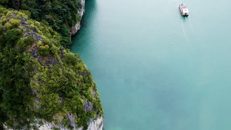 Halong-Bay-Vietnam-tourist-boat-drone-video-over-sea-and-green-limestone-pillars-mountain