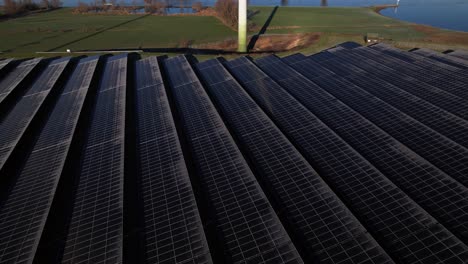 Paneles-Solares-Con-Lenta-Revelación-Aérea-De-Una-Sola-Turbina-De-Molino-De-Viento-En-Los-Países-Bajos-Parte-De-La-Industria-Sostenible-En-El-Paisaje-Invernal-Holandés