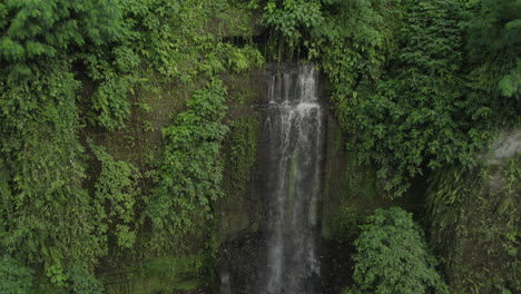 Secret-waterfall-hidden-in-the-jungle-near-Ubud-in-Bali,-Indonesia,-drone-pan-right-shot,-close-up-view
