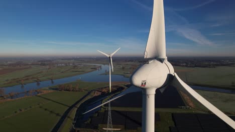 Wind-turbine-seen-from-up-close-with-solar-panels-in-The-Netherlands-part-of-sustainable-industry-Dutch-along-river-IJssel-and-Twentekanaal-waterway