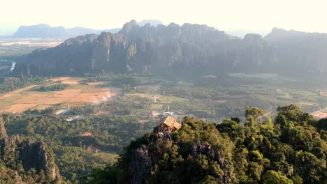 Kleine-Bambushütte-Auf-Einem-Berggipfel-Bei-Sonnenuntergang-In-Laos-Mit-Herrlichem-Blick-Auf-Die-Grüne-Und-Sandige-Landschaft