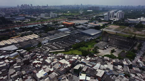 Aerial-view-over-the-Vila-Nova-Jaguare-ghetto-towards-a-industrial-area,-in-sunny-Sao-Paulo,-Brazil