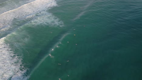 Aerial-views-over-surfers-at-Burleigh-Heads-at-sunrise,-Gold-Coast,-Queensland,-Australia