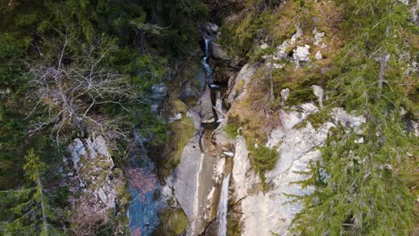 Zeitlupenflug-Rückwärts-Aus-Der-Luft-Eines-Mehrstufigen-Wasserfalls-In-Den-Alpen,-Schweiz