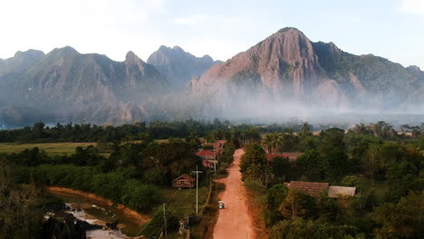 Sany-Road-Hacia-Montañas-Nubladas-En-Laos-Mientras-Drone-Vuela-Alto