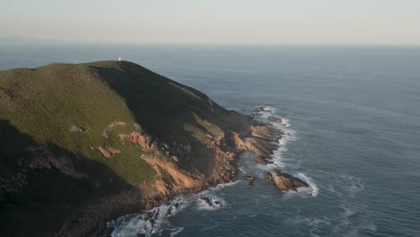Südafrika-Robberg-Naturreservat-Grüne-Landzunge-Mit-Felsen-Und-Meereswellen,-Die-Darunter-Krachen