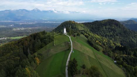 Iglesia-En-La-Cima-De-Una-Colina-En-El-Impresionante-Paisaje-Montañoso-De-Eslovenia,-Vuelo-Aéreo-De-Drones