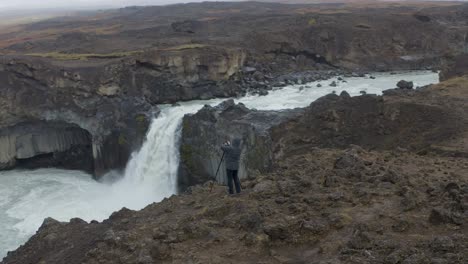 Vista-Aérea-Del-Fotógrafo-Tomando-Una-Foto-De-La-Caída-De-La-Cascada-Aldeyjarfoss-En-Las-Tierras-Altas-De-Islandia