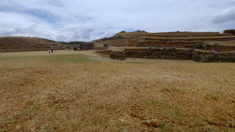 Wide-shot-of-tourists-at-the-fort-ruins-of-Sacsayhuaman,-Cusco,-Peru