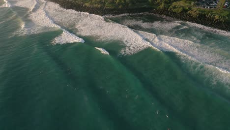 Aerial-views-over-surfers-at-Burleigh-Heads-at-sunrise,-Gold-Coast,-Queensland,-Australia