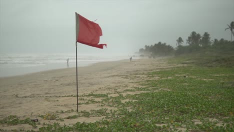 Rote-Fahne-Weht-Am-Strand,-Filmische-Aufnahme,-Wellen-Im-Hintergrund