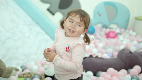 Glückliches-Kleines-Mädchen,-Das-Laut-Lacht,-Während-Es-In-Der-Kindertagesstätte-Mit-Bunten-Plastikbällen-Spielt