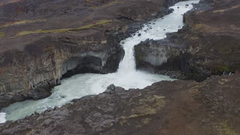 Aerial-backwards-shot-of-Aldeyjarfoss-Waterfall-between-rocky-mountains-of-Iceland