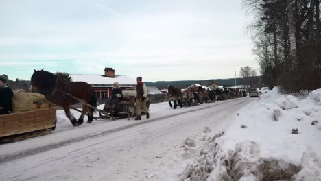 Una-Larga-Fila-De-Trineos-Tirados-Por-Caballos-Con-Personas-Vestidas-Con-Viejos-Paños-Contemporáneos-Que-Viajan-En-Un-Paisaje-Invernal