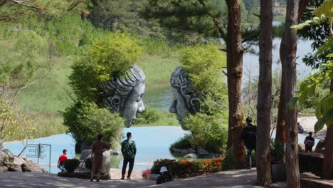 People-Sightseeing-With-A-Couple-Of-Giant-Head-Sculptures-At-Clay-Tunnel,-Dalat-City,-Vietnam