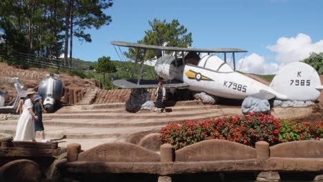 Visitors-explore-the-Da-Lat-Sculpture-Museum,-where-they-see-a-clay-motorcycle-and-a-clay-plane-on-display