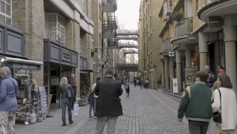 Schwenken-Sie-In-Zeitlupe-Auf-Die-Kopfsteinpflasterstraße-Von-London-Shad-Thames-Mit-Menschen-Und-Fahrrädern