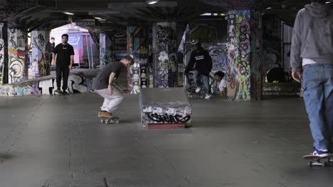 Ein-Skateboarder-Macht-Einen-Trick,-Während-Leute-Im-Skatepark-Southbank-Centre,-London,-Großbritannien,-Skateboard-Fahren-Und-Zuschauen