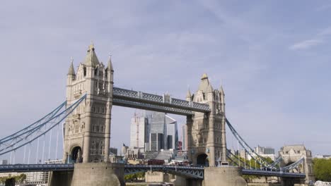 Tilting-down-to-Tower-Bridge-below-view-in-clear-sunny-day-with-car-traffic-and-tourists