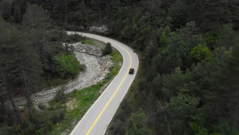 Drone-Video-Seguimiento-Seguimiento-Coche-Montaña-Bosque-De-Pinos-Salvajes-Camino-Sinuoso-Gramos-Grecia