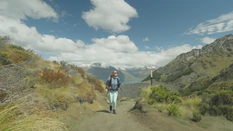 Mujer-En-Forma-Con-Mochila-Caminando-Por-Un-Sendero-Empinado-De-Montaña-En-Nueva-Zelanda