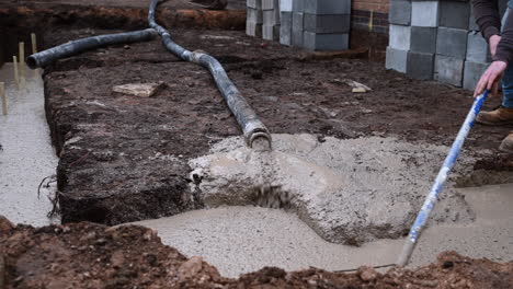 Concrete-mix-being-laid-into-a-foundation-site-using-a-concrete-pump,-at-a-domestic-home-construction-site-in-the-UK