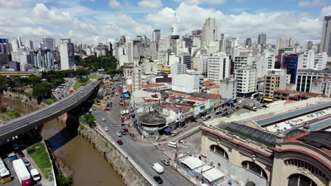 Aerial-view-rising-over-the-Tamanduatei-river-towards-the-skyline-of-Sao-Paulo,-sunny-Brazil