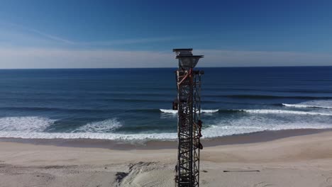 Aerial-orbiting-shot-of-tower-at-sandy-beach-of-Praia-de-Mira-during-Beautiful-sunny-day-with-blue-ocean-in-backdrop