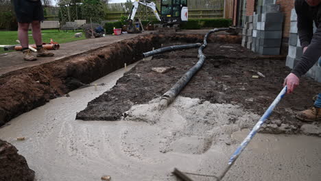 Concrete-mix-being-laid-into-a-foundation-site-using-a-concrete-pump,-at-a-domestic-home-construction-site-in-the-UK