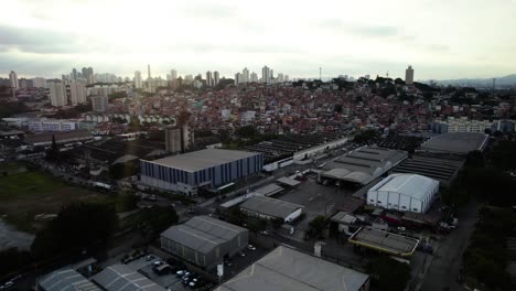Aerial-view-over-a-industrial-area-towards-the-Jaguare-favela,-sunset-in-Sao-Paulo,-Brazil