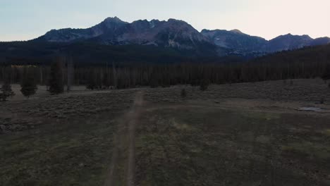 4K-Drone-fly-over-country-field-at-dusk-in-the-Sawtooth-Mountains,-Stanley-Idaho