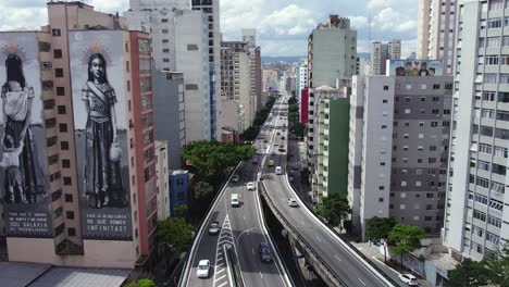 Static-aerial-view-cars-driving-on-a-road-in-middle-of-tall-buildings-in-Sao-Paulo,-Brazil
