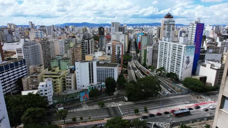 Aerial-view-flying-in-middle-of-buildings-towards-traffic-on-the-Minhocao-highway-in-sunny-Sao-Paulo,-Brazil