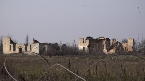 Ein-Mord-An-Krähen-Fliegt-über-Zerstörte-Gebäude-Im-Dorf-Posad-Pokrovs&#39;ke,-Dem-Zentrum-Der-Heftigsten-Kämpfe-Zwischen-Ukrainischen-Und-Russischen-Truppen-Zu-Beginn-Des-Krieges